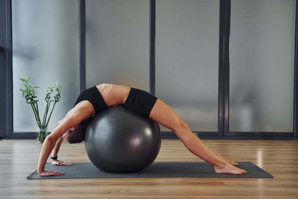 femme travaillant sa souplesse avec un ballon yoga