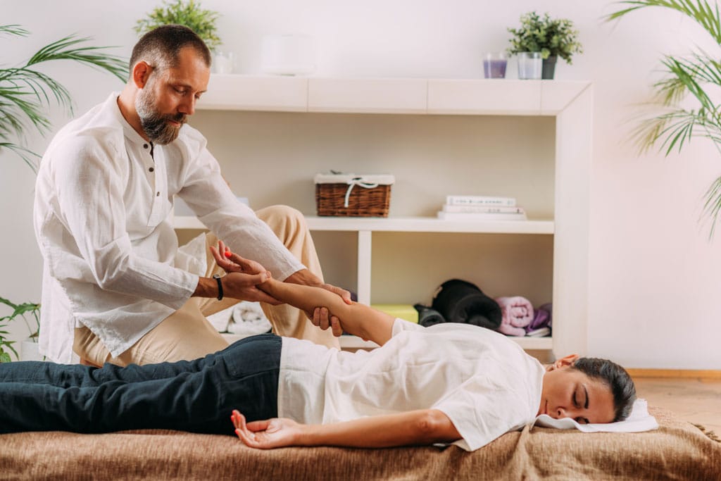 praticien pratique un massage shiatsu sur le bras dune femme