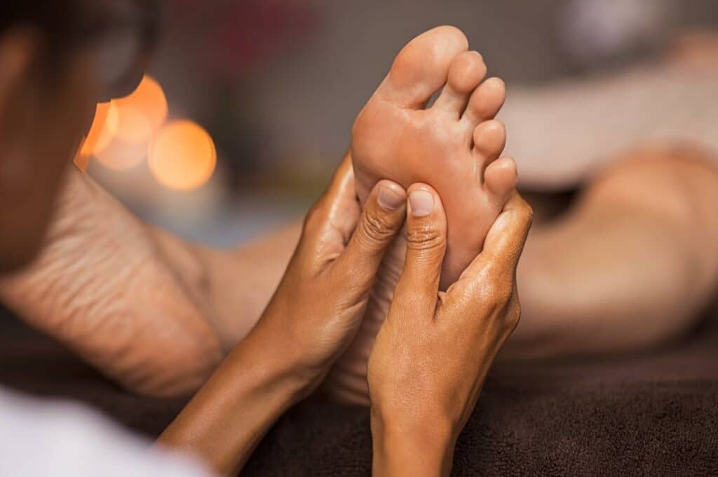 masseur effectue un massage de réflexologie plantaire sur le pied d'une femme